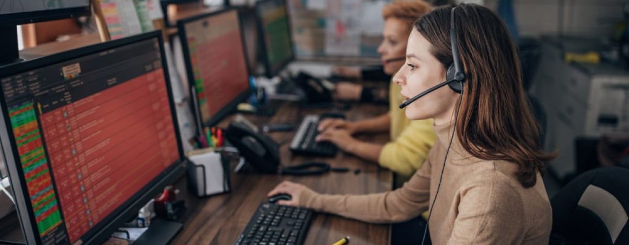 Call center agents at work, one wearing a headset, focused on computer screens displaying call data, illustrating Dazonn Assist's outbound call center services.